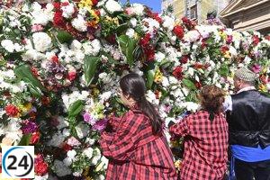 Vibrante celebración con ofrenda floral a la Virgen del Pilar en un día soleado.